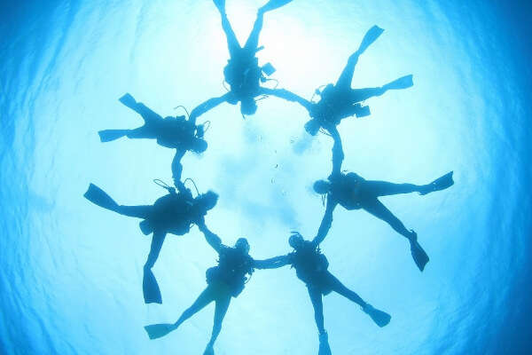 ダイビングをして水中でみんなで丸を作っている写真