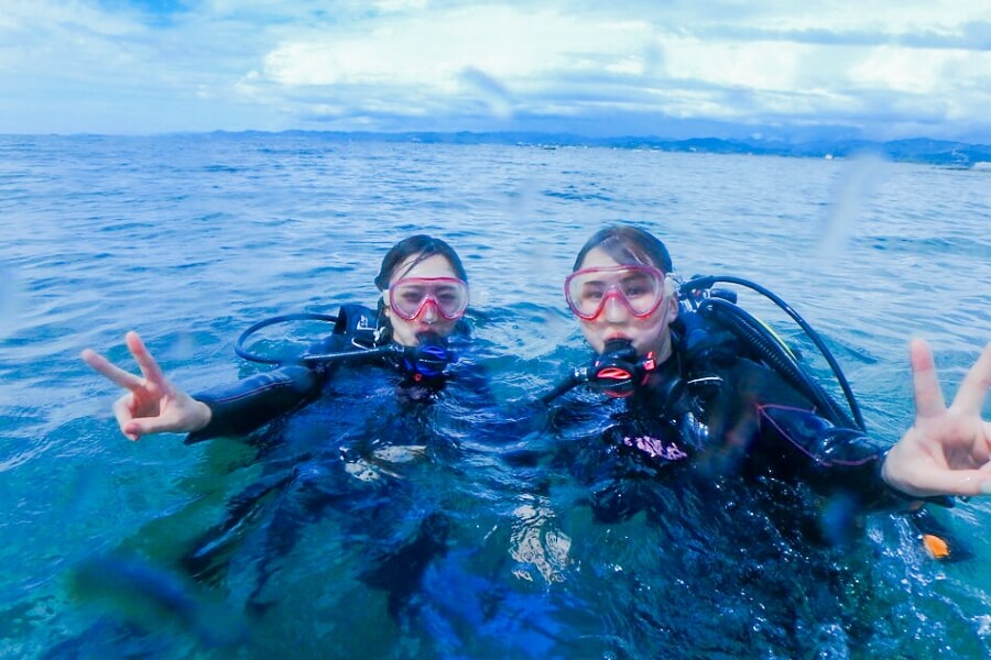 体験ダイビング中にカメラに向かってピースをする女性2人の写真